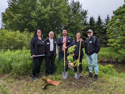 Nicole Cox (NVCA Board Member), Christopher Baines (NVCA Board Member), Jonathan Scott (NVCA Vice Chair), Andrea Khanjin (Minister of the Environment, Conservation and Parks), Doug Hevenor (CAO of NVCA) stands beside a newly planted tree in the Minesing Wetlands.